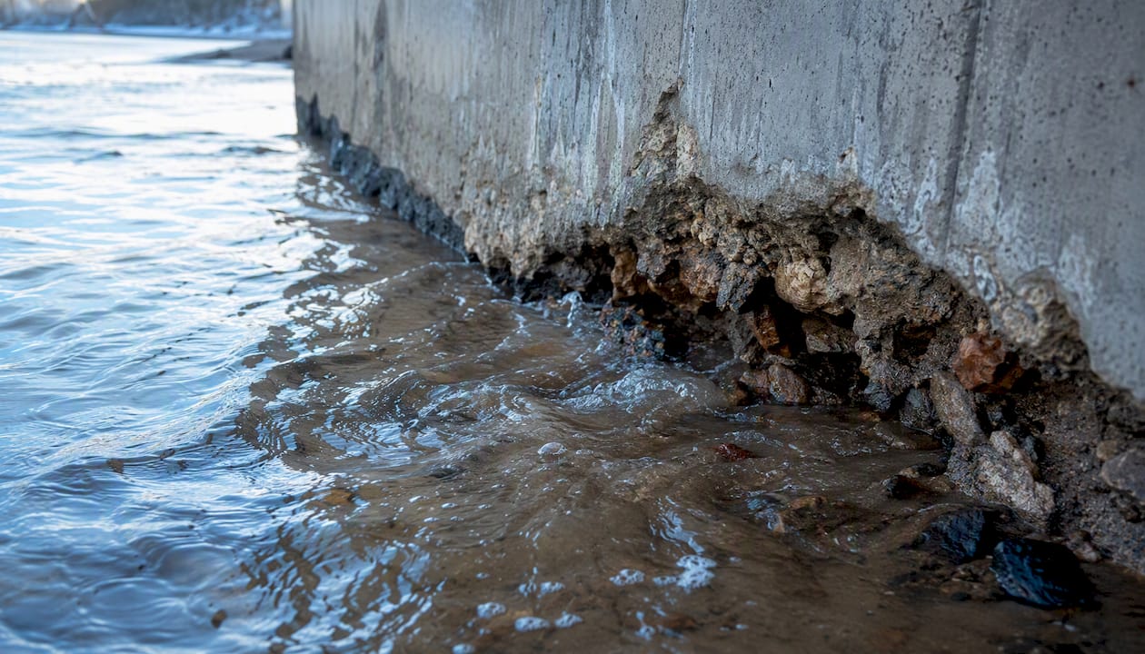 Scoured base of seawall with turbulent water