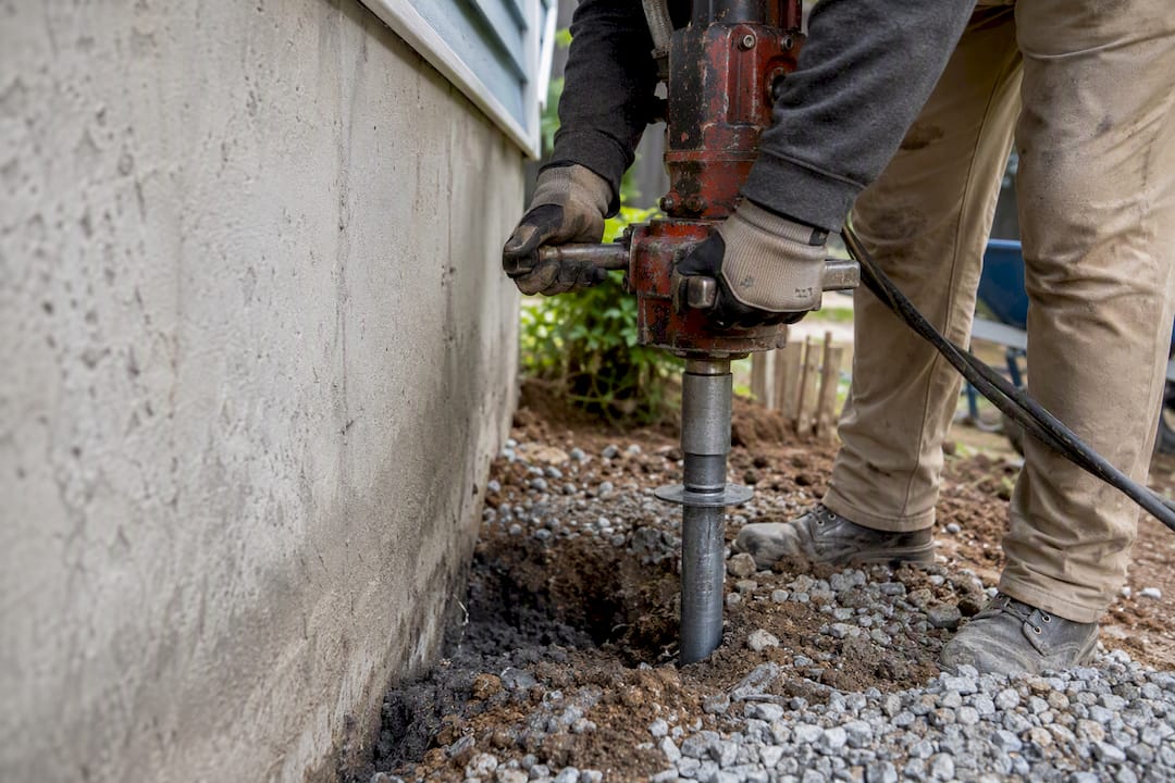 Worker installing helical pier for foundation repair
