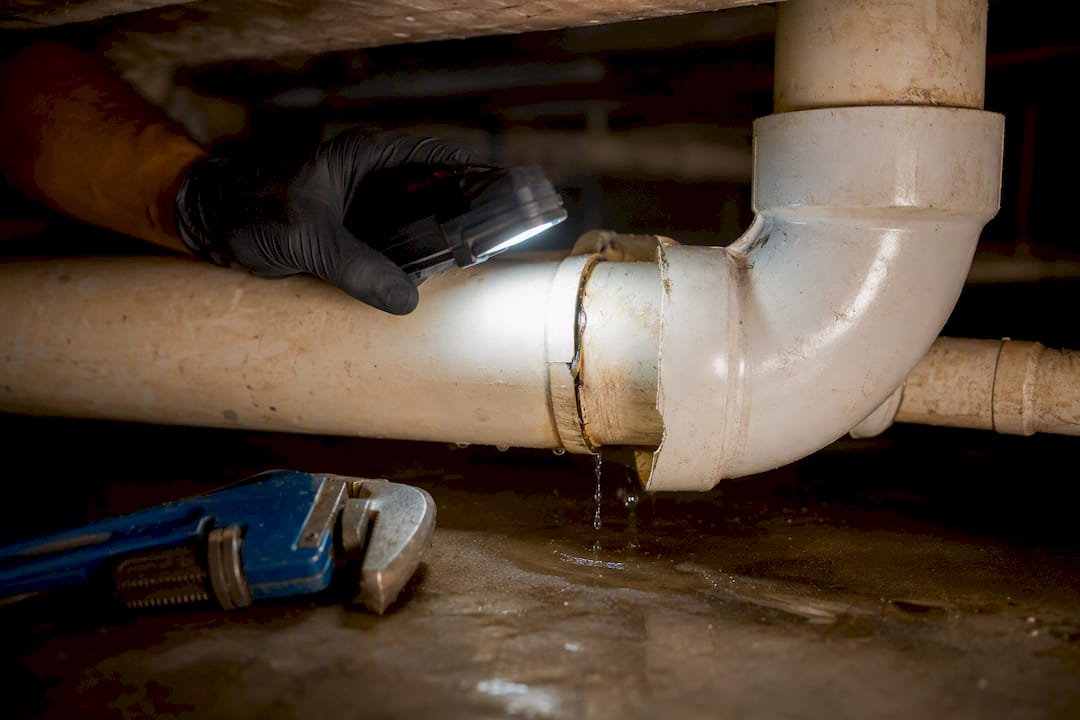 Plumber inspecting leaking crawl space waste line