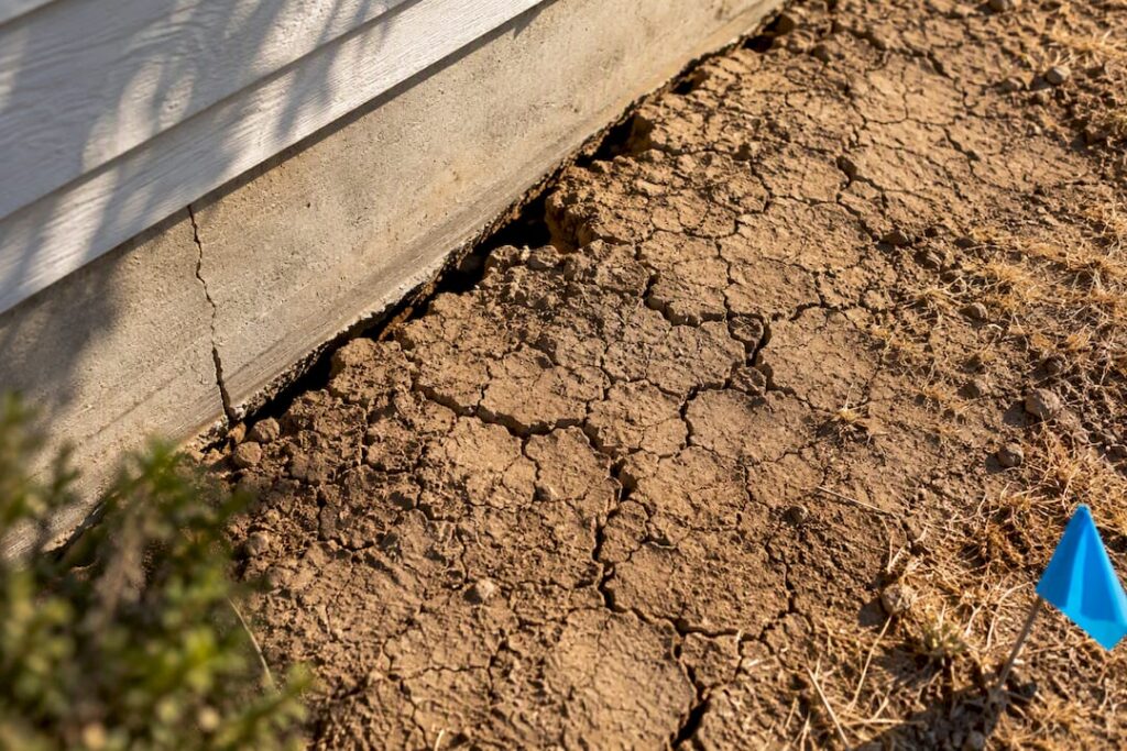 Cracked drought soil beside foundation edge